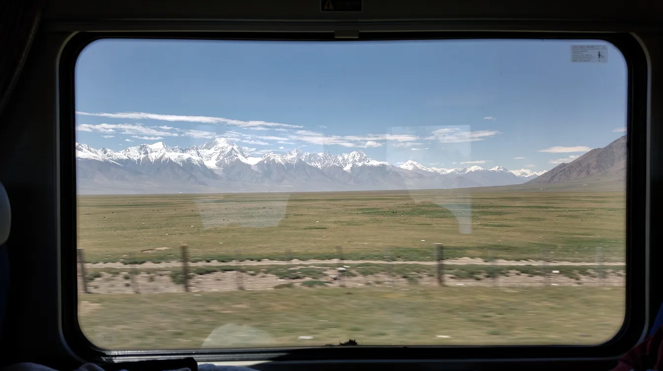 Der Blick aus dem Zugfenster zeigt die beeindruckende tibetische Hochebene mit schneebedeckten Bergen und weiten Graslandschaften, die die majestätische Kulisse für den Potala Palast in Lhasa bilden. Diese Region ist ein bedeutendes Zentrum des Buddhismus und ein Wahrzeichen des tibetischen Kulturerbes.